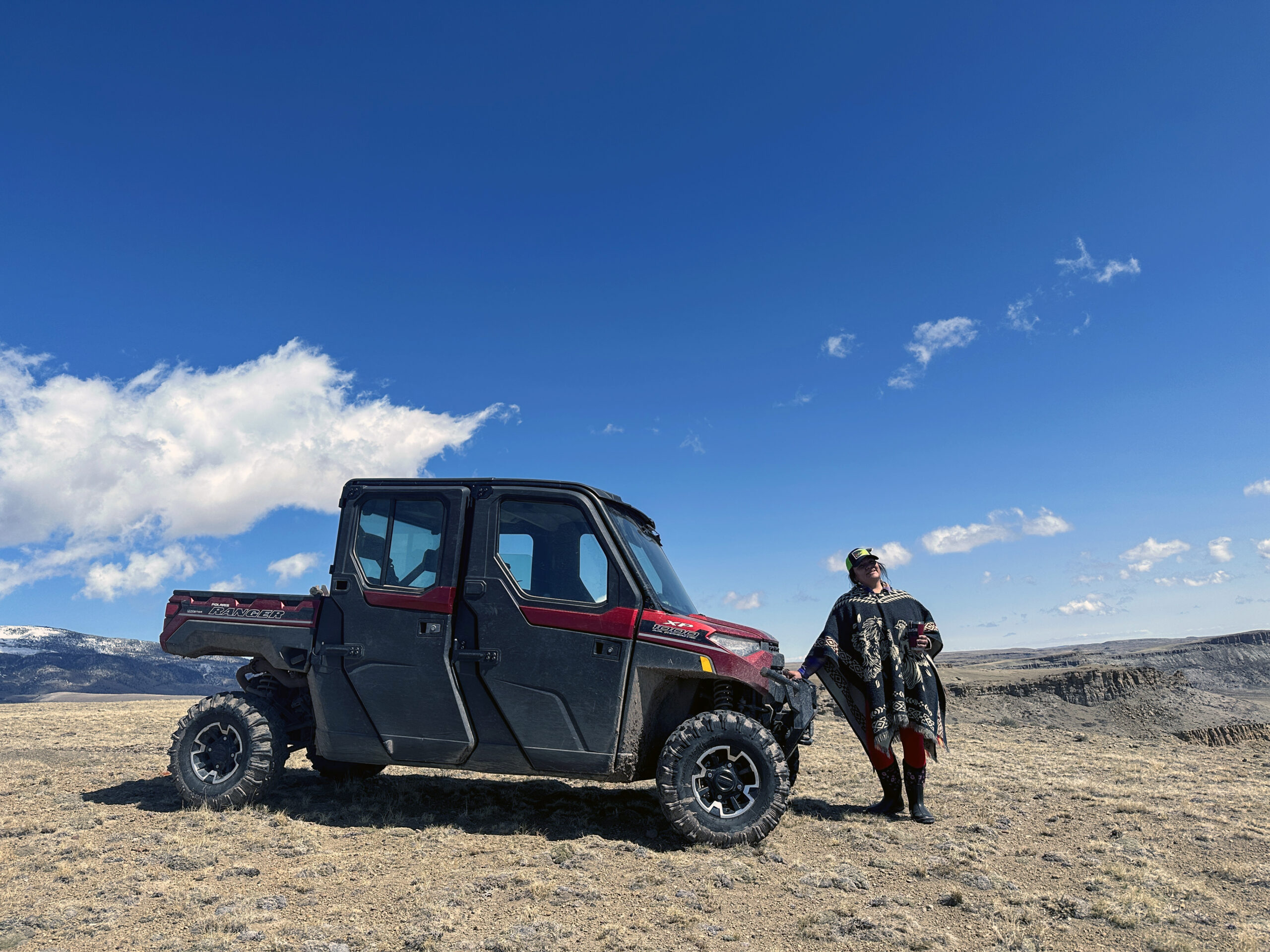  A woman stands beside a black off-road utility vehicle. 
