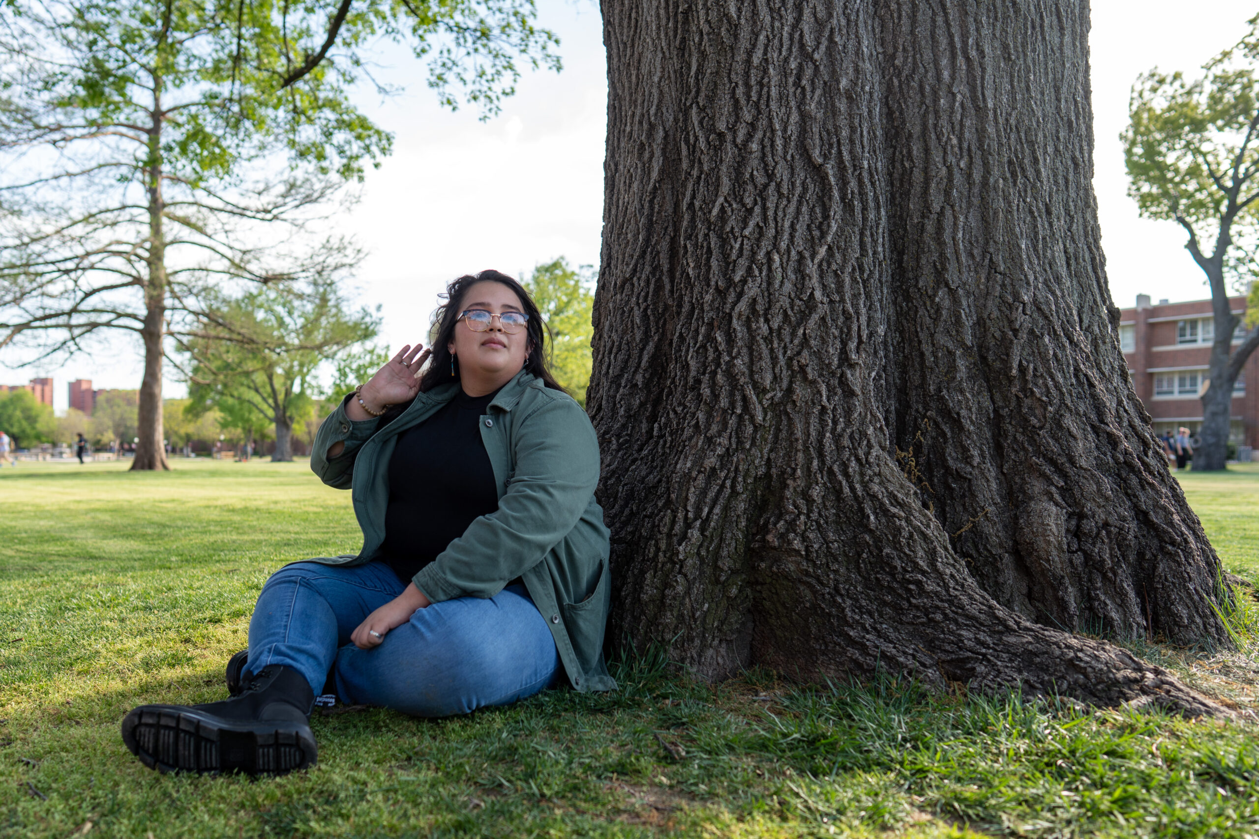 Ella sits beneath a tree on the University of Oklahoma campus, gazing up to the sky.