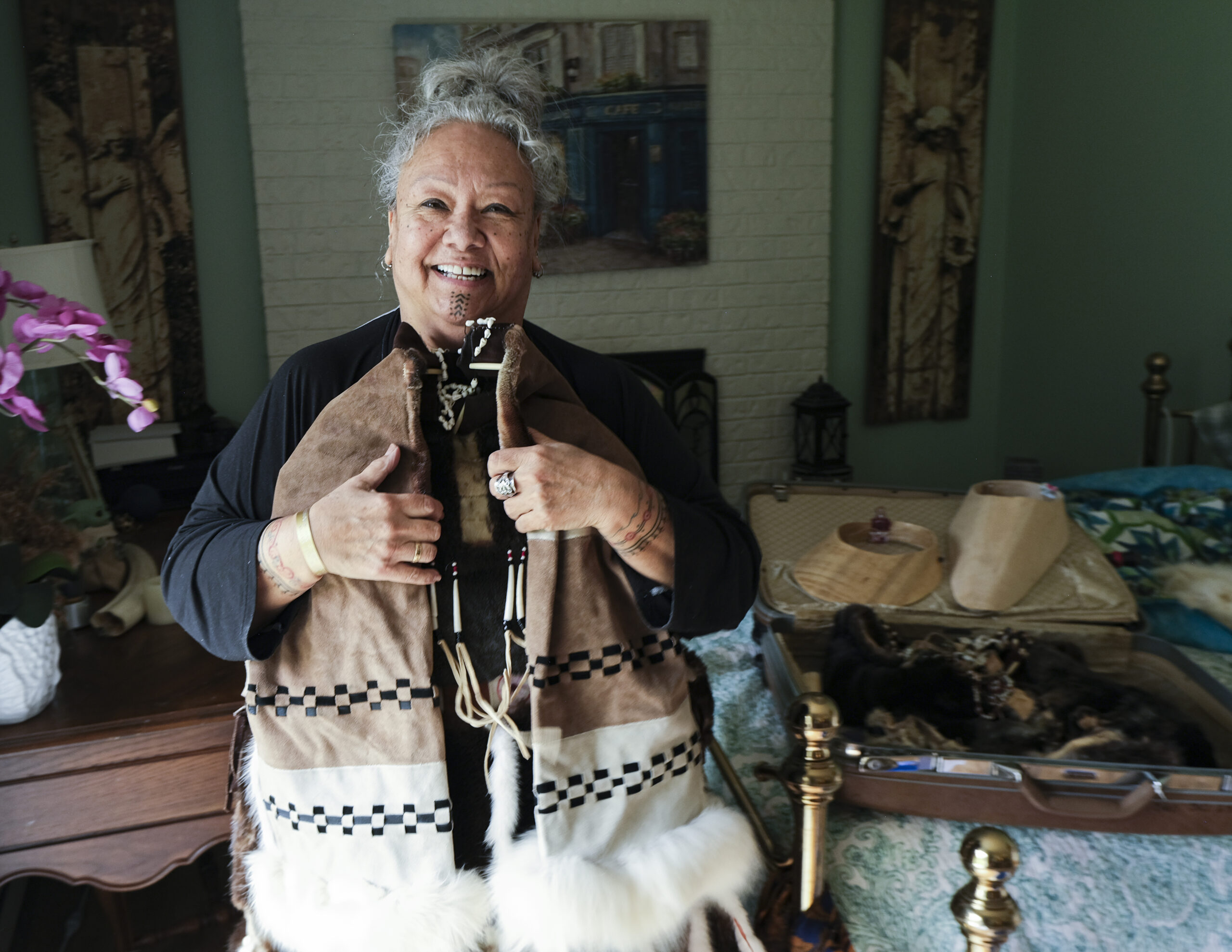Unangax̂ elder with traditional face and wrist tattoos, holding her hand-stitched dance regalia.