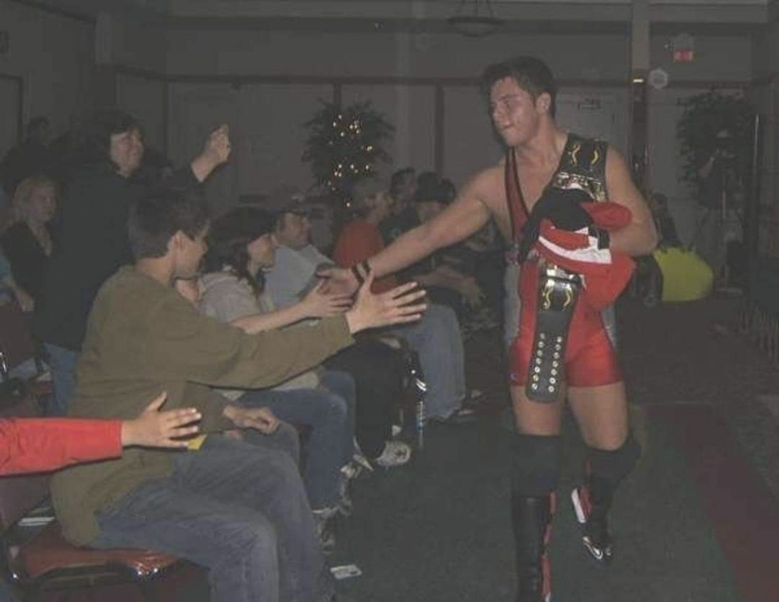 Stefan Richard, professional wrestler, walks past a group of fans with a championship belt.