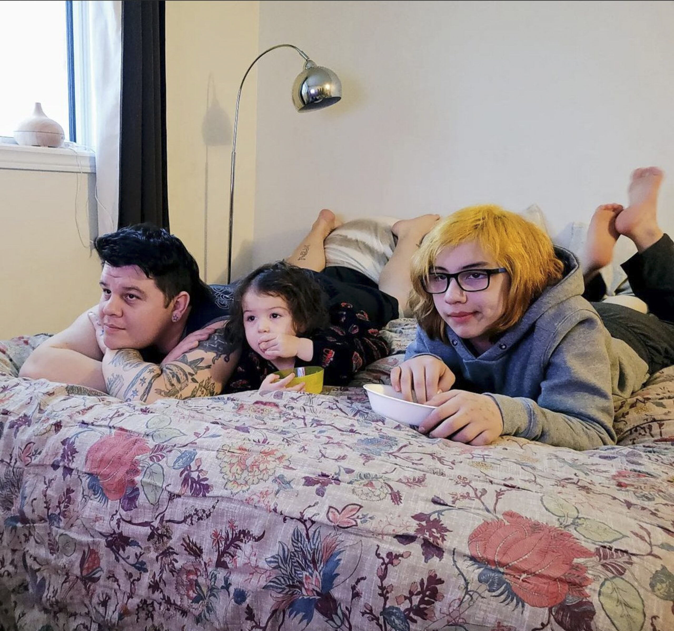 Stefan Richard, his children Rainbow & Arizona watching a movie together in a row of three on the bed.